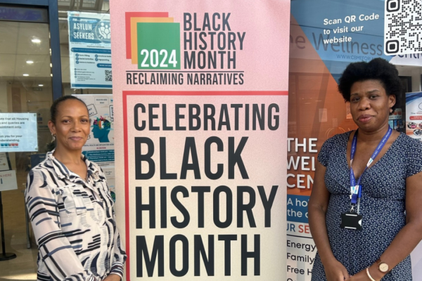 Two women standing in front of a Black History Month Banner